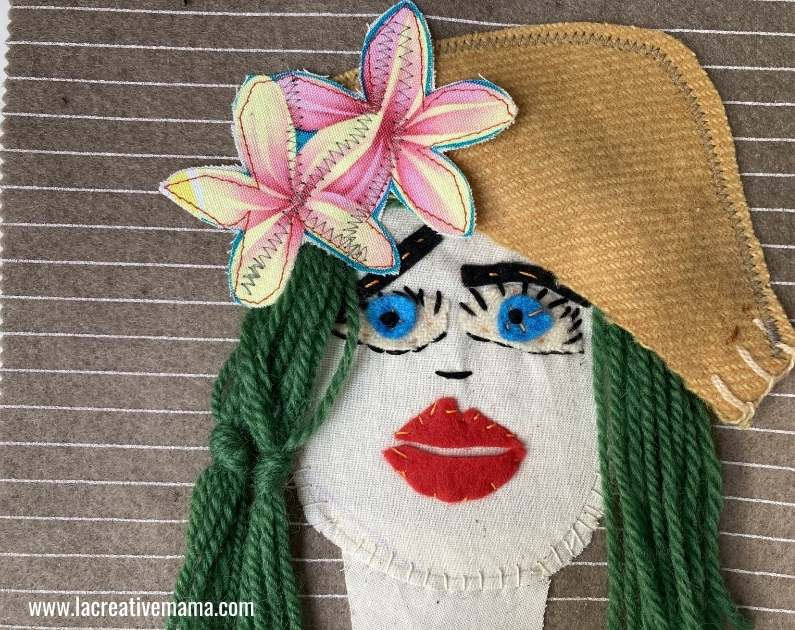 final result of the embroidered portrait using wool hair, applique flower and upcycled wool hat