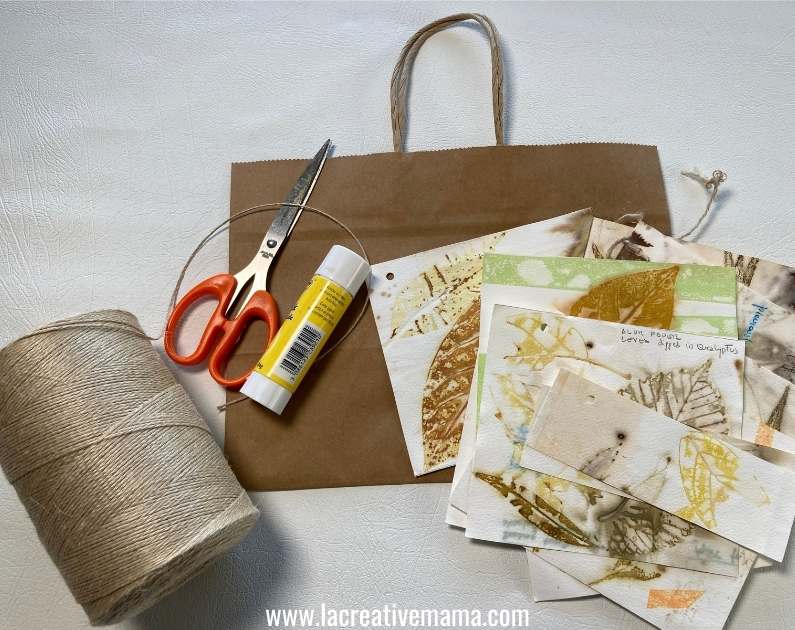 a variety of materials needed for this tutorial. scissors, twine, paper bags, eco prints on paper and glue