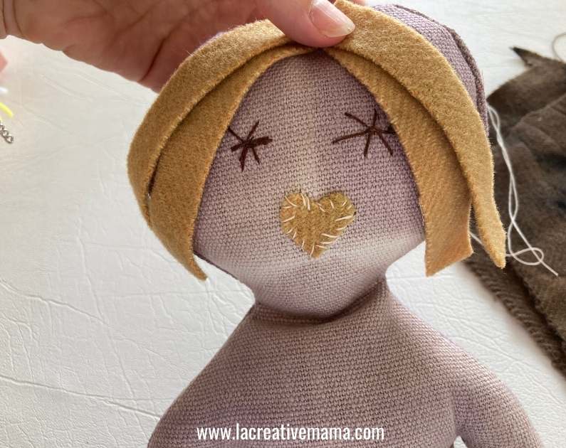 sewing the hair to the head of the rag doll