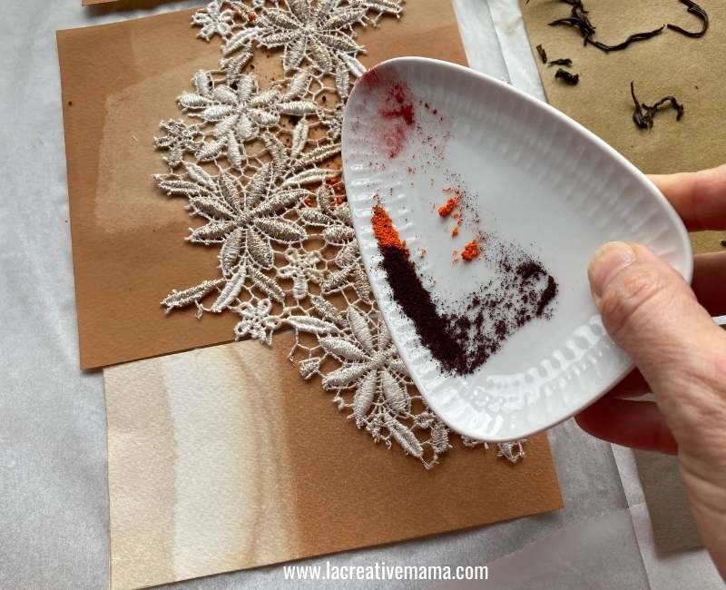 using lace to create texture on a tea dyed paper by sprinkling food dye on top of the lace 