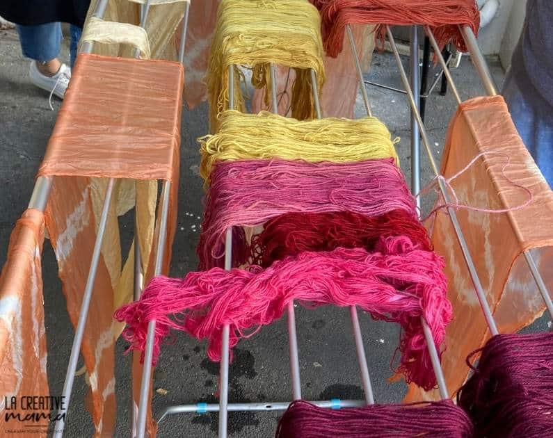 7 wool skeins hanging out to dry on a wire rack. these skeins were dyed using cochineal, madder root and eucalyptus 