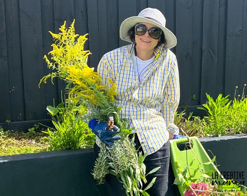 a photo of Victoria Martinez Azaro in the garden holding a bunch of fresh goldenrod flowers and leaves 